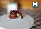 1:12 scale miniature sliced berry chocolate layer cake with colorful layers and raspberries, on a white table