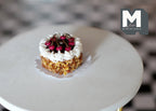 1:12 scale miniature cherry cake with cream and chopped nuts, topped with red cherries, on a round white table