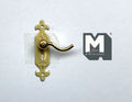 1:12 scale miniature polished brass door lever with ornate backplate and keyhole, shown on a white background