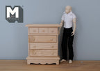 1:12 scale miniature unpainted wood chest of drawers with 4 drawers and shaped base, beside an artist figure