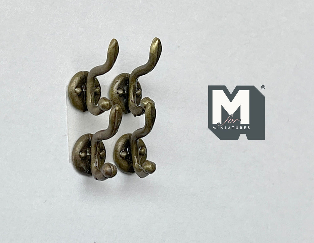 1:12 scale miniature antique bronze wall hooks with double curved prongs, set of 4, on a white surface