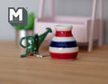 1:12 scale miniature ceramic flower vase with red, white and navy horizontal stripes, shown beside a green watering can