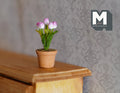 1:12 scale miniature potted tulips in pink and white in a terracotta pot, shown on the edge of a wood table