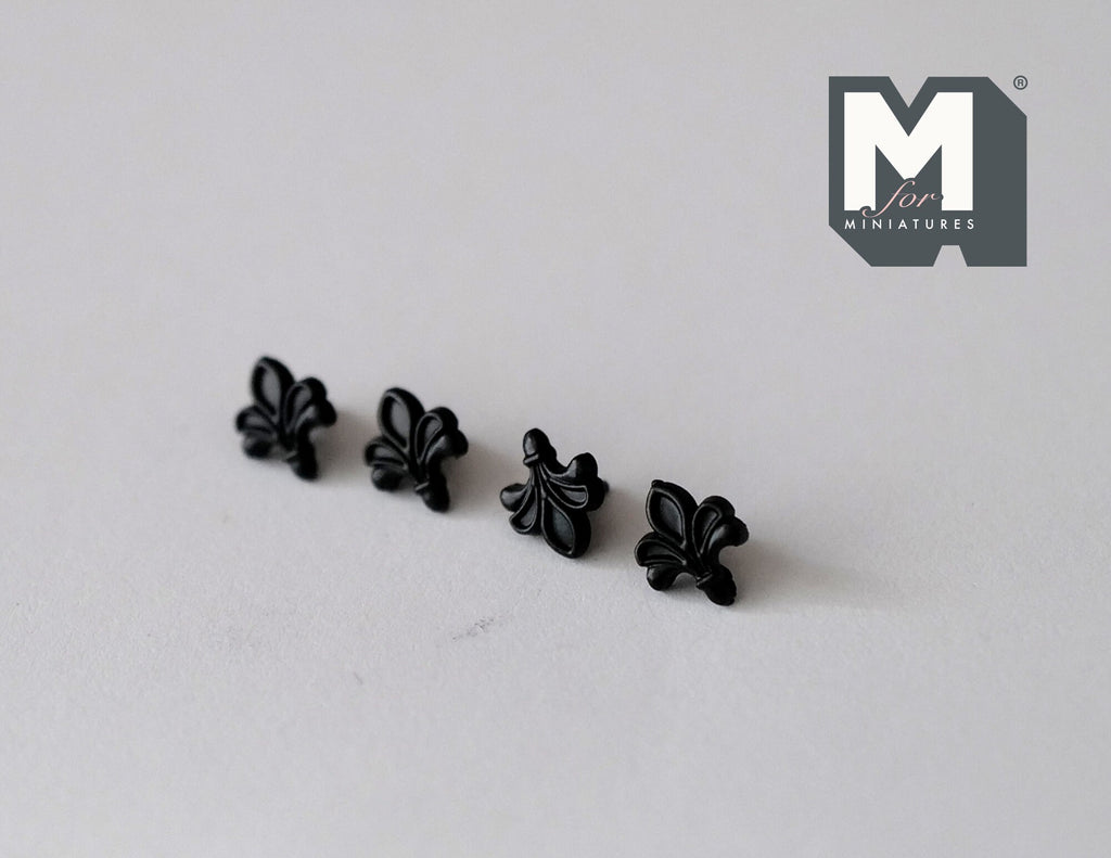 1:12 scale miniature matte black fleur de lis cabinet knobs, set of 4, lined up on a white surface