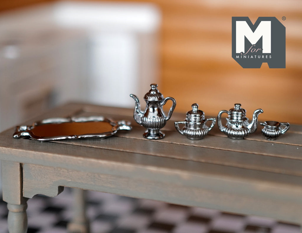 1:12 scale miniature silver holloware tea service with 2 teapots, sugar bowl, creamer and tray, set of 5, on a table