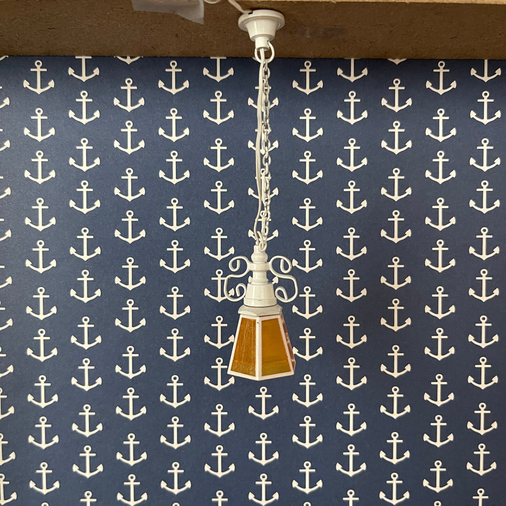 1:12 scale miniature chain drop pendant light with amber glass shade, 12V with plug, hanging against navy anchor wallpaper