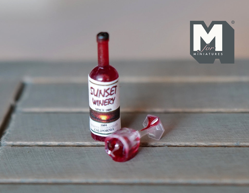 1:12 scale miniature spilled wine set with a red wine bottle and tipped glass, shown on a gray wood table