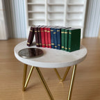 1:12 scale miniature hardcover books with gold edges in brown, red, blue and green, set of 12, on a round side table