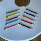 1:12 scale miniature colored pencils, set of 10 in assorted colors, shown on a white table beside a coin