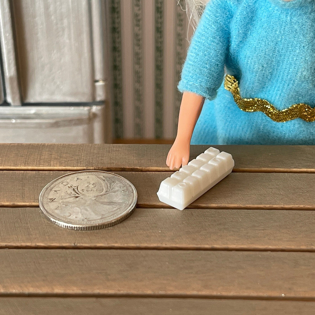 1:12 scale miniature closed egg carton in white, 1 dozen, on a wood table beside a coin for scale