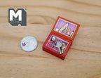 1:12 scale miniature vanity box in red with mirror and accessories, pink lined, shown open beside a coin