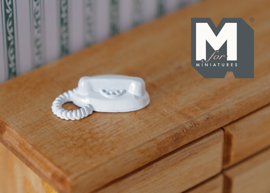 1:12 scale miniature push button telephone in white with a coiled cord, shown on a wood dresser