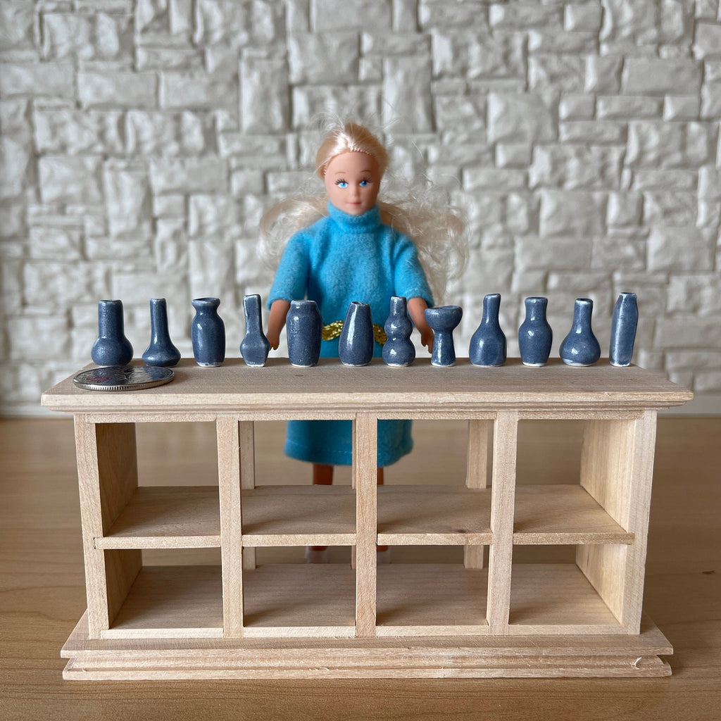 1:12 scale miniature ceramic vases in slate blue, assorted shapes, extra small, set of 12, lined up on a wood counter