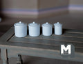 1:12 scale miniature kitchen canisters with lids in white, set of 4 graduated sizes, shown in a row on a gray table