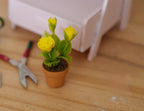 1:12 scale miniature potted yellow roses in a clay pot, shown on a wood floor beside garden shears and a pink bench