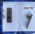 1:12 scale miniature door knobs with keyhole plates and keys in bronze, set of 2, shown in clear blister packaging