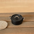 1:12 scale miniature black metal cooking pot with handles and lid, medium, shown on a wood table beside a coin