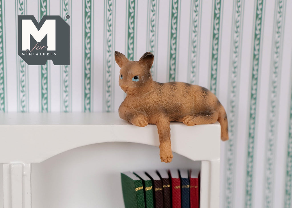 1:12 scale miniature ginger tabby cat shelf sitter with paws over the edge, shown lying on top of a white bookcase