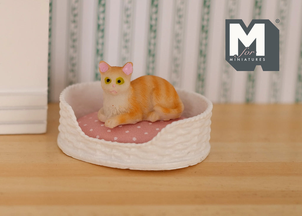 1:12 scale miniature lying kitten in orange tabby with white chest, shown resting in a white pet bed