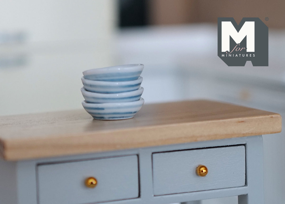 1:12 scale miniature white ceramic bowls, set of 4, shown stacked on a gray kitchen cabinet with a wood top