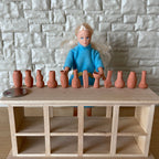 1:12 scale miniature terracotta vases in assorted shapes, set of 12, extra small, lined up on a wood shelf by a doll