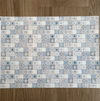 Miniature azure embossed Mediterranean tile sheet, light blue and white patterned tiles, full sheet on a wood floor