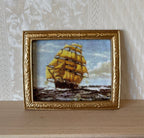1:12 scale miniature framed sailing ship painting in an ornate gold frame, tall ship on rough seas, leaning on a wall