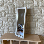 1:12 scale miniature full length floor mirror with a white frame, shown leaning against a stone wall