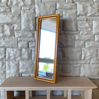 1:12 scale miniature wood full length floor mirror in amber finish, rectangular, leaning against a white stone wall