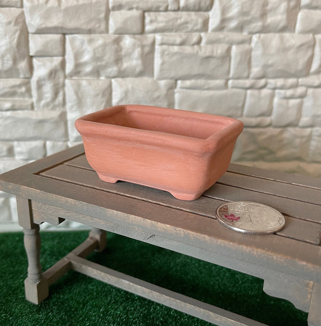 1:12 scale miniature terracotta trough planter with feet, rectangular with a rolled rim, on a garden table beside a coin