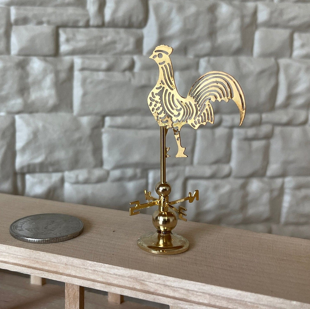 1:12 scale miniature brass rooster weather vane on stand with compass arrows, shown beside a coin on a wood shelf