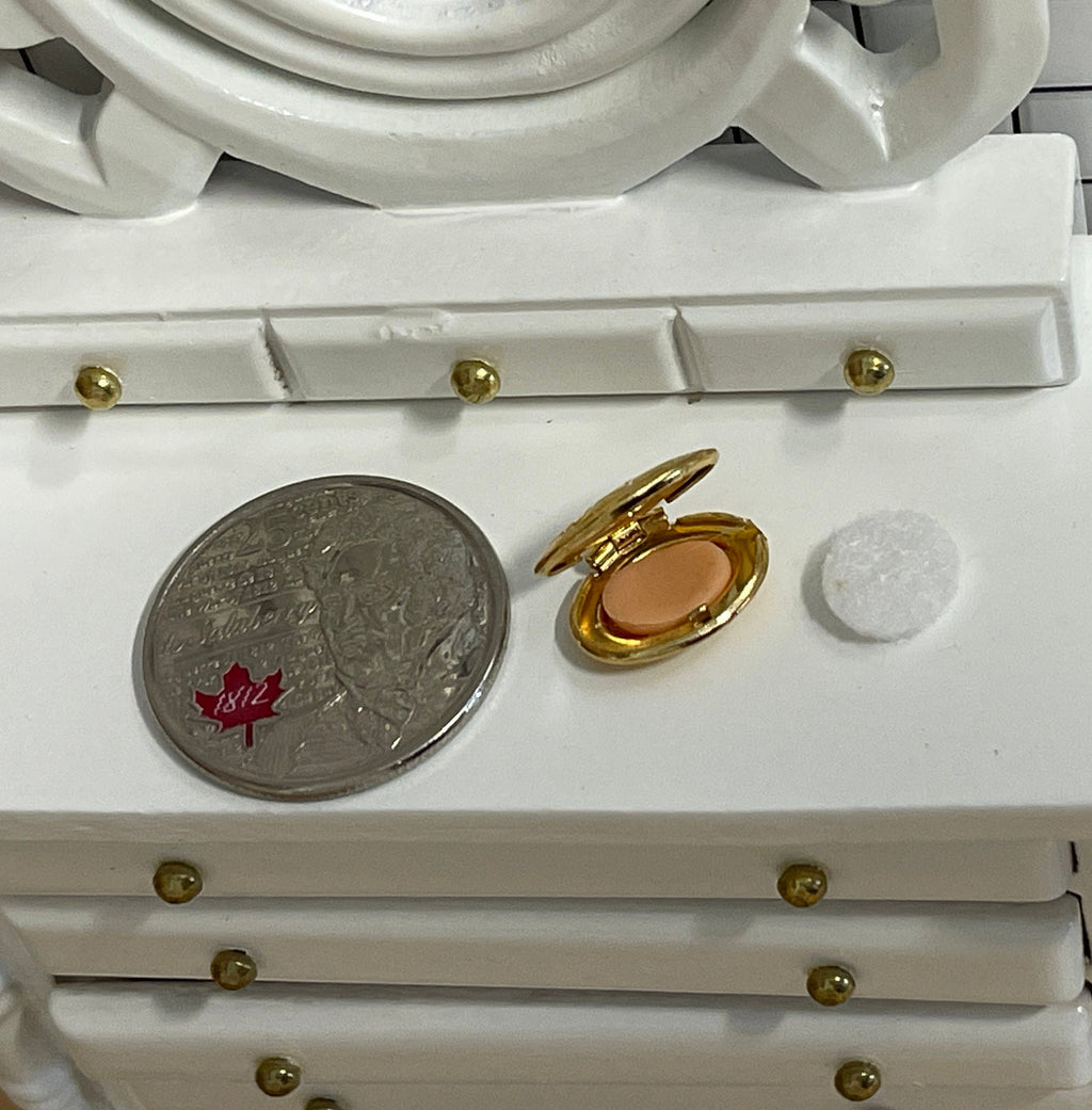 1:12 scale miniature makeup compact in gold with clasp, powder puff and embossed floral lid, open on a vanity by a coin