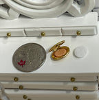 1:12 scale miniature makeup compact in gold with clasp, powder puff and embossed floral lid, open on a vanity by a coin