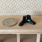 1:12 scale miniature children's lace up boots in black, pair, shown beside a coin on a wood shelf