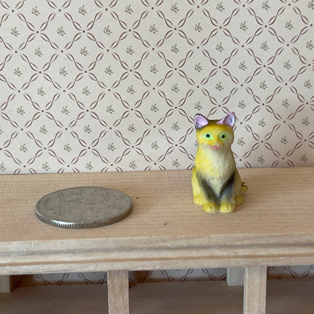 1:12 scale miniature sitting tabby cat in tan with dark stripes, style B, shown on a wood shelf beside a coin