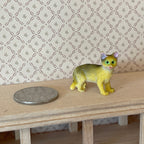 1:12 scale miniature standing tabby cat in tan with dark stripes, shown beside a coin on a wood shelf