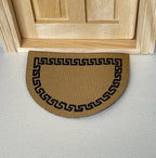 1:12 scale miniature tan half moon doormat with black Greek key border, shown in front of a wood door
