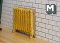 1:12 scale miniature gold antique style column radiator with ornate relief, shown against a white tile wall