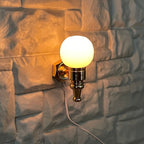 1:12 scale miniature globe wall sconce, 12V LED plug in, brass with a white globe, shown lit on a stone wall