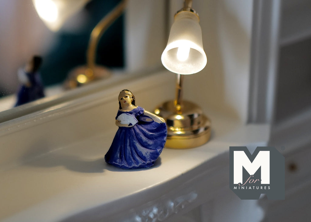 1:12 scale miniature dancing lady figurine in a blue gown, shown on a white mantel beside a lit table lamp