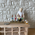 1:12 scale miniature beer tap tower in brass with 4 pump handles, shown on a wood bar with a figure, mugs and a coin
