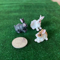 1:12 scale miniature bunny rabbit figures, set of 3 in gray, white and tan with white, on green grass beside a coin