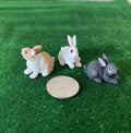 1:12 scale miniature bunny rabbit figures, set of 3, style C, tan, white and gray, shown on green grass beside a coin