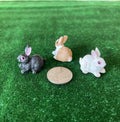1:12 scale miniature bunny rabbit figures, set of 3 in gray, tan and white, shown on green grass beside a coin