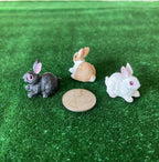 1:12 scale miniature bunny rabbit figures, set of 3 in gray, tan and white, shown on green grass beside a coin