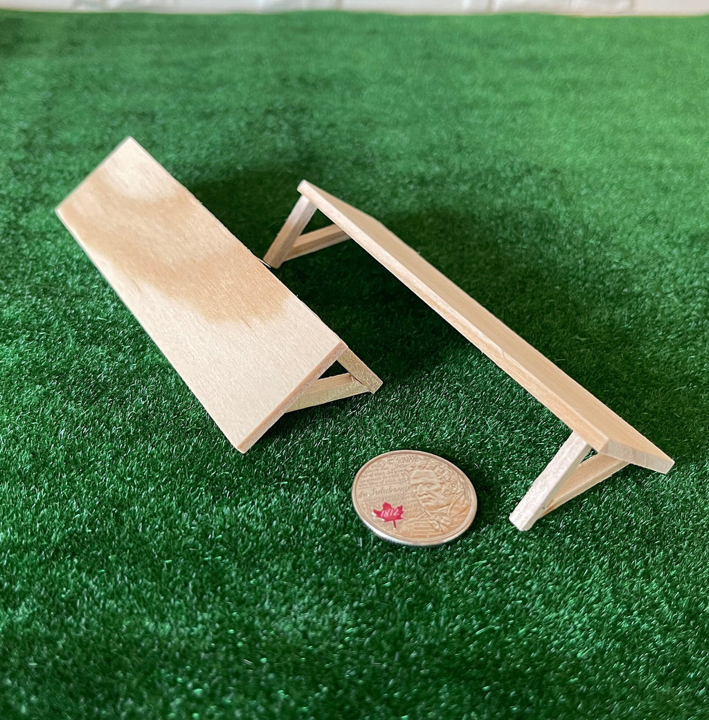 1:12 scale miniature unpainted wood wall shelves with triangle brackets, set of 2, on green turf beside a coin