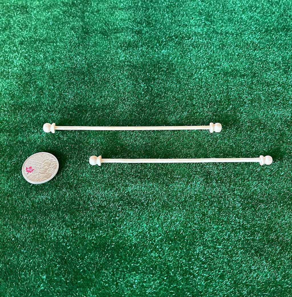 1:12 scale miniature unpainted wood curtain rods with ball finials, set of 2, on green turf beside a coin for scale