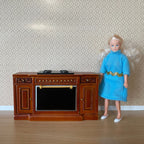1:12 scale miniature wood kitchen range cabinet in brown with cooktop and oven, shown beside a doll for scale