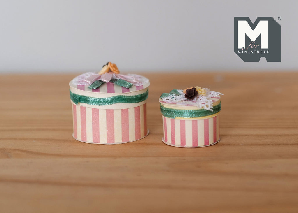 1:12 scale miniature striped hat boxes with floral lids, set of 2, pink and white stripes, shown on a wood surface