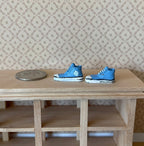1:12 scale miniature blue sneakers with white soles and laces, 1 pair, on a wood shelf beside a coin for scale